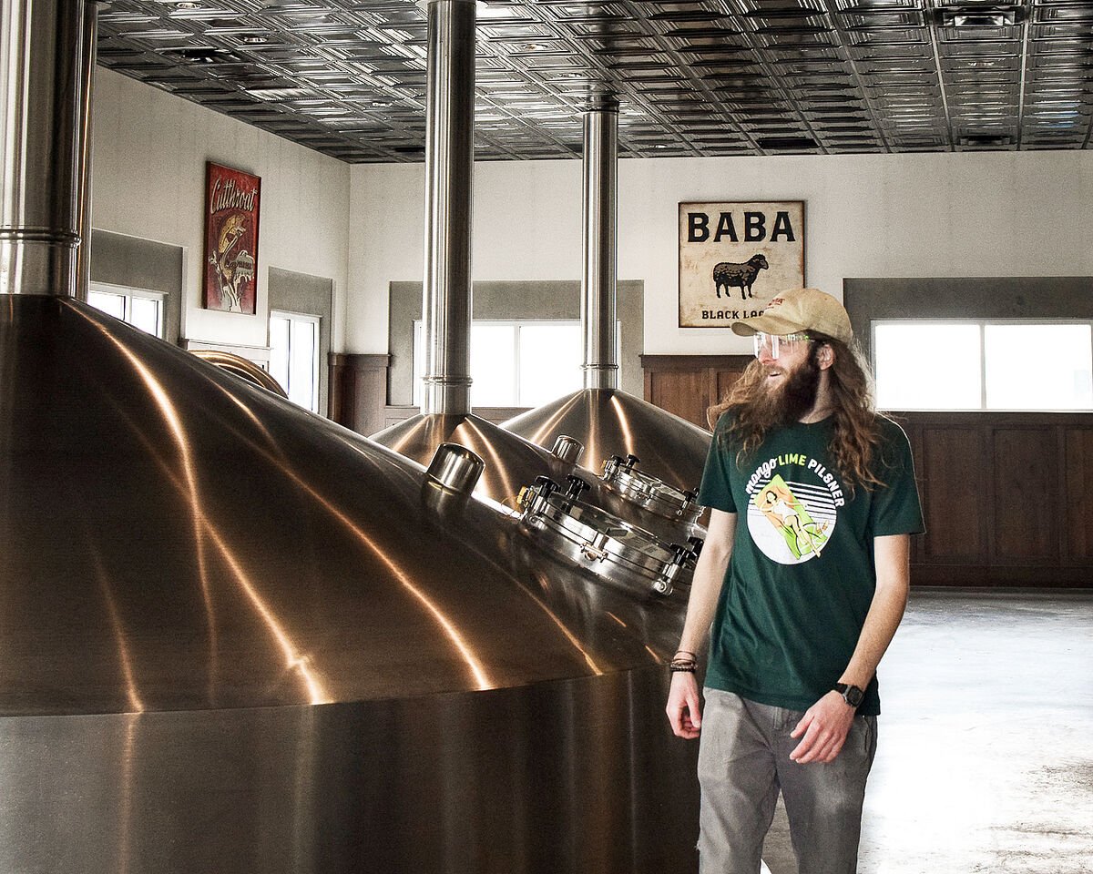 uinta brewer strolls by a fermentation tank in the brewhouse