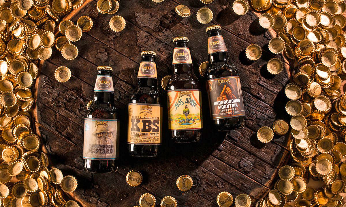 founders brewing co. barrel aged series next to bottle caps atop a barrel